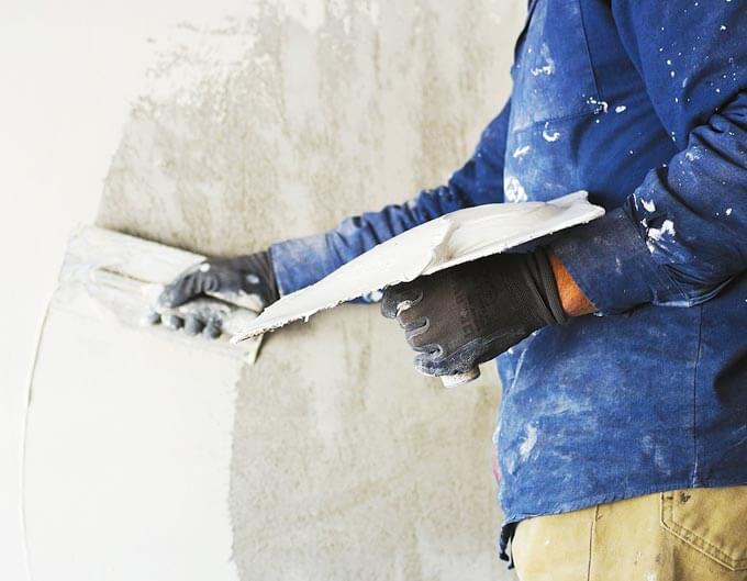Albañil aplicando estuco en muro
