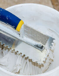 Bote con mezcla de cemento blanco con llana en su interior