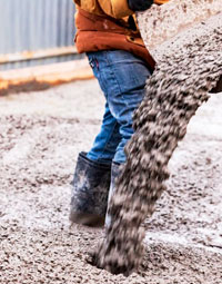 Trabajador vertiendo mezcla de cemento gris en una construcción