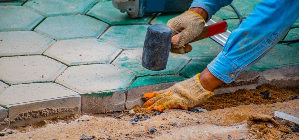 Especialista colocando losetas de concreto con forma hexagonal sobre una capa de arena