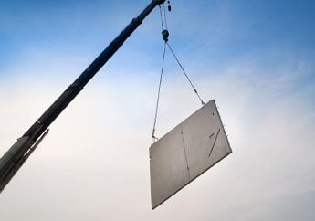 Grúa elevando un muro de concreto prefabricado para instalarlo en un edificio