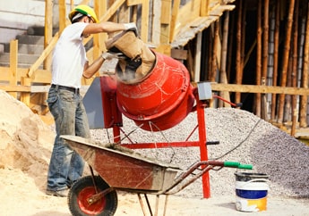 Albañil utilizando una mezcladora para revolver materiales de construcción