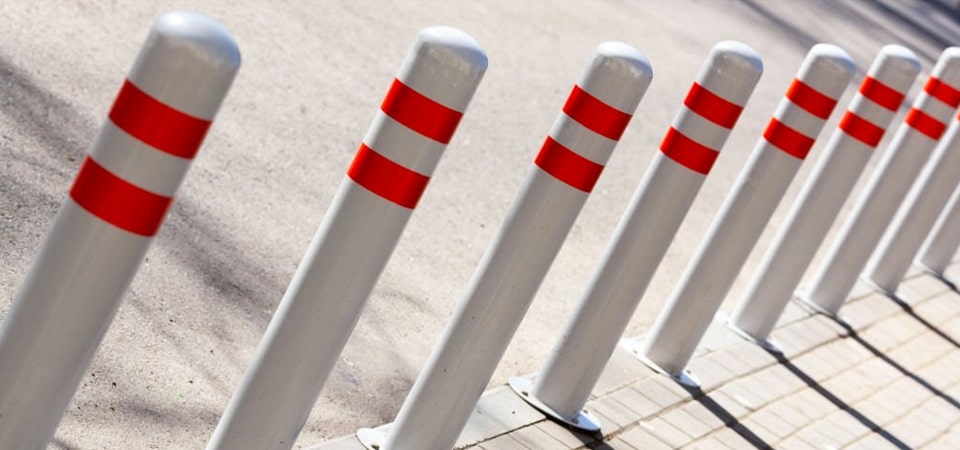 bolardos de seguridad pintados de rojo en un estacionamiento