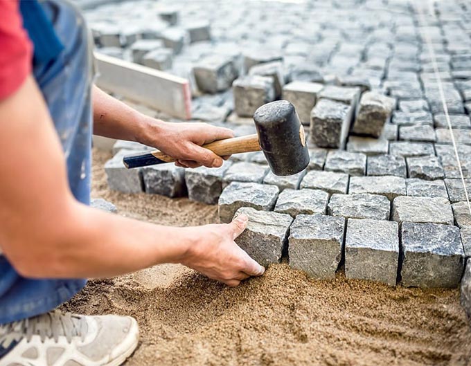 Trabajador de la construcción armando un sendero de adoquines Trabajador de la construcción armando un sendero de adoquines