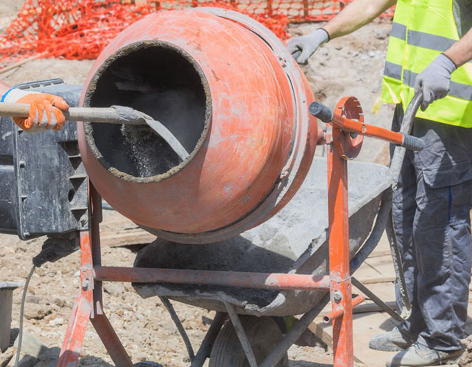 Trabajadores de la construcción preparando mezcla en una revolvedora de concreto pequeña