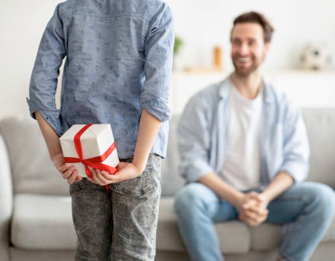 Niño entregando regalo sorpresa para celebrar día del padre