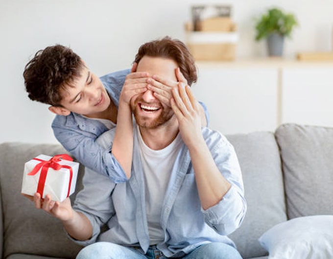 Niño cubriendo ojos a su papá para sorprenderlo con regalo de día del padre