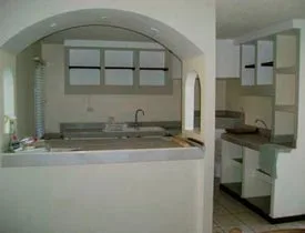 Cocina pequeña de concreto y tablaroca con arco sobre barra dispuesta como desayunador 